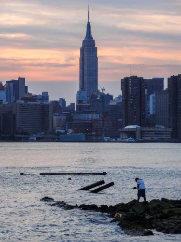 The Empire State Building rises beyond the East River at dusk
