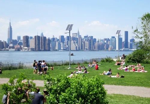 Visitors relax on the lawn with Midtown Manhattan visible across the river