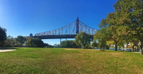 The Queensboro Bridge can be seen across the park's open lawn