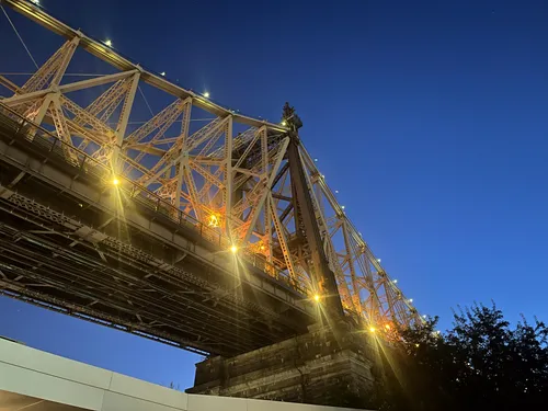 The Queensboro Bridge's steel cantilever structure lit up at dusk