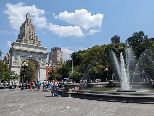 Water jets soar from the Washington Square Fountain with the arch beyond