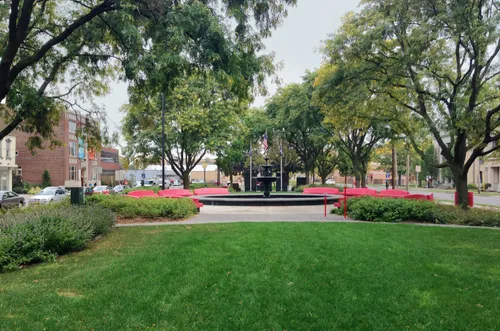 Red benches are arranged in a circle around the central fountain at Forman Park