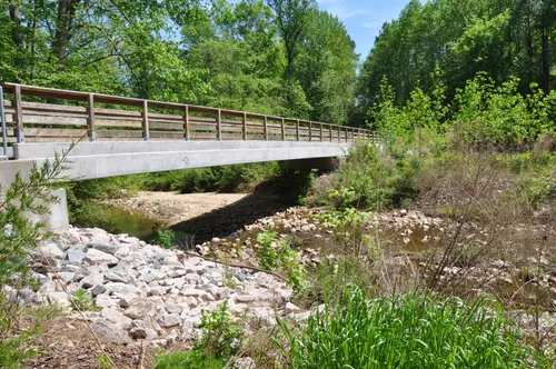A bridge spans the stream in a natural setting