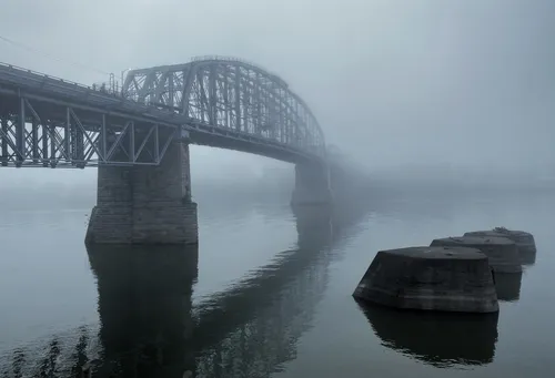 Morning fog shrouds the bridge creating a moody riverside atmosphere