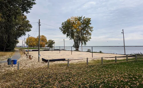 The sand volleyball courts near the lake with leaves covering the ground