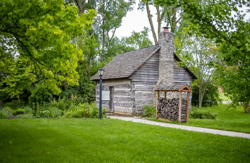 The Jarusiewic Cabin with stacked firewood sits among mature trees
