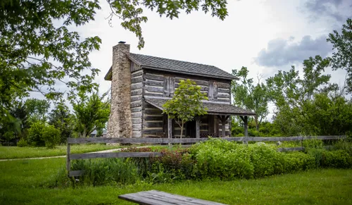 The Harshman House with stone chimney surrounded by greenery