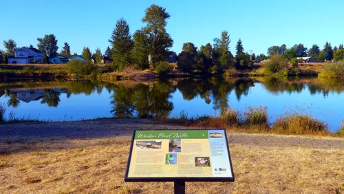 An interpretive sign stands beside the still water