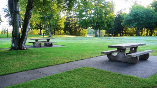 Two picnic tables under large trees offer a quiet spot to rest