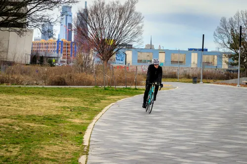 A cyclist rides along the tiled riverfront path