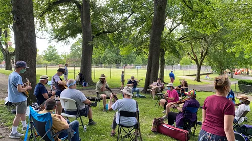 A group of musicians gathers on the lawn for an afternoon performance