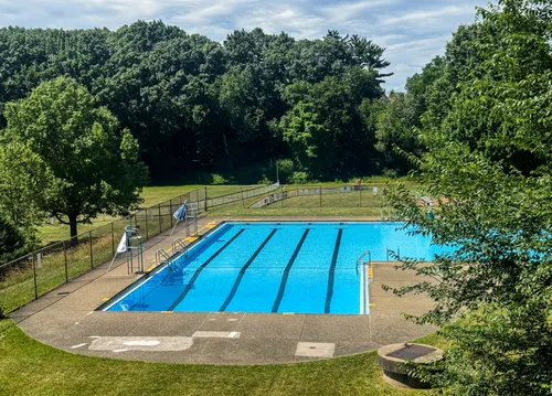 The pool sits among green lawns and mature trees