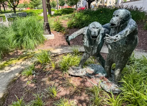 Two bronze primates lean toward each other among the greenery