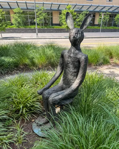 A slightly unsettling rabbit sits quietly amid tall grasses