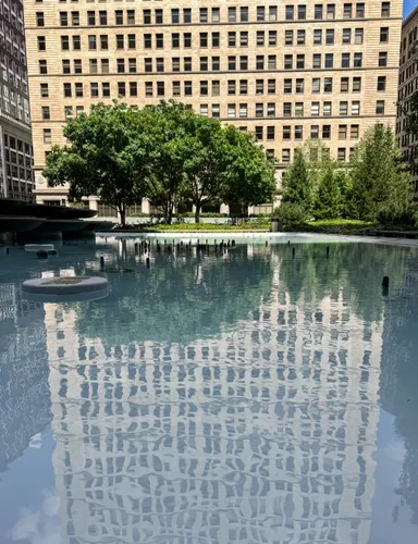 The reflecting pool mirrors the surrounding buildings on a calm day