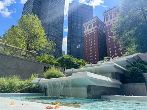 Water features and geometric stonework with the historic Omni William Penn Hotel visible in the background