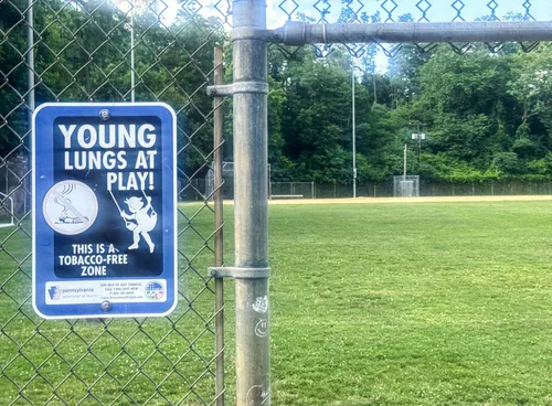 A tobacco-free zone sign posted along the fence of the athletic field