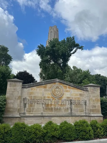 The Cathedral of Learning peeks out from behind a tree north of the plaza