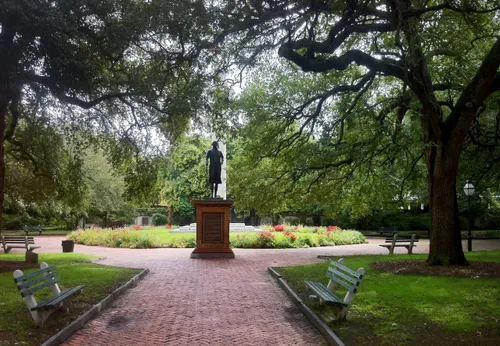 A brick pathway leads to the George Washington statue with the  Washington Light Infantry memorial behind