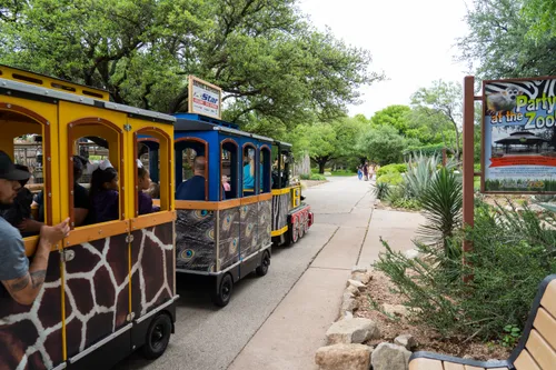 A colorful train carries passengers through pathways at Abilene Zoo