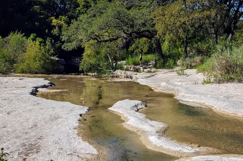 Shallow stream winding through rock beds in the park
