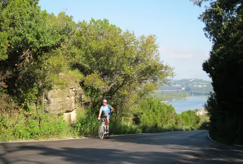 Cyclist ascending Mt Bonnell Road with river views in the distance