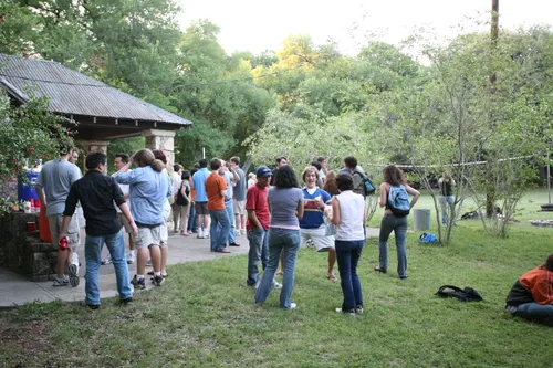 A group of visitors is gathered near a covered stone shelter