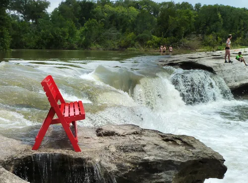 A bright red bench perched above Upper McKinney Falls