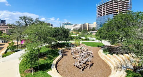 A wood and rope play structure sits within the mulched play area