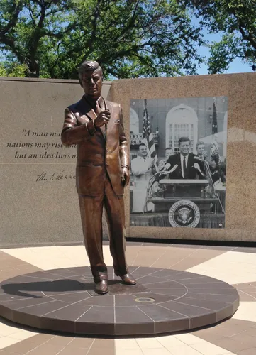 The 8-foot bronze JFK statue in General Worth Square with the granite memorial wall behind it