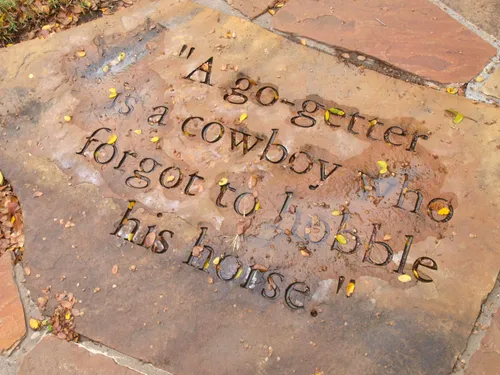 Engraved stone quote about a cowboy who forgot to hobble his horse
