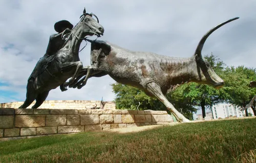 Bronze sculpture depicting a cowboy on horseback herding cattle