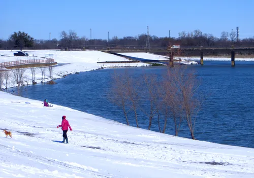 A visitor walks her dog along the snowy lakeshore on a winter day