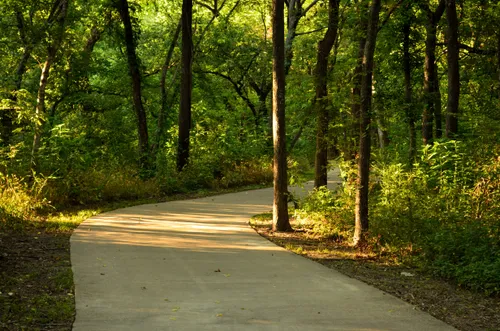 A paved path curves through the dense tree cover at Breckinridge Park