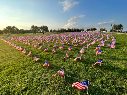 American flags dot the park's green lawn at sunset