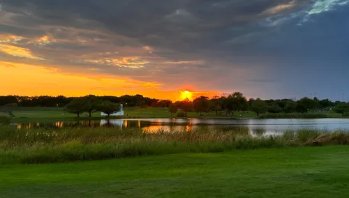 The sun sets over the reservoir under a dramatic sky