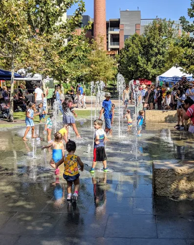 Children splash at the water feature on a sunny day