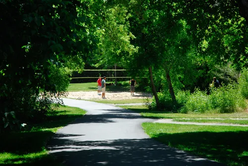 A paved walking path winds through the lush green trees at Canyon Glen Park