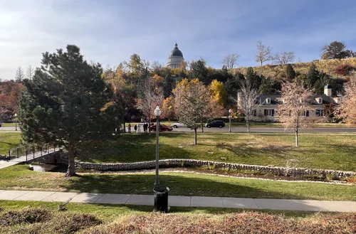 The Utah State Capitol is visible beyond the park landscape