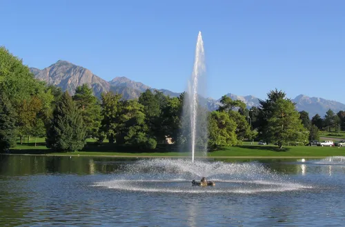 A fountain sprays water skyward with Mount Olympus visible in the background