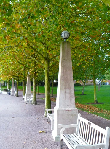 Tree-lined pathway with decorative light posts and white benches