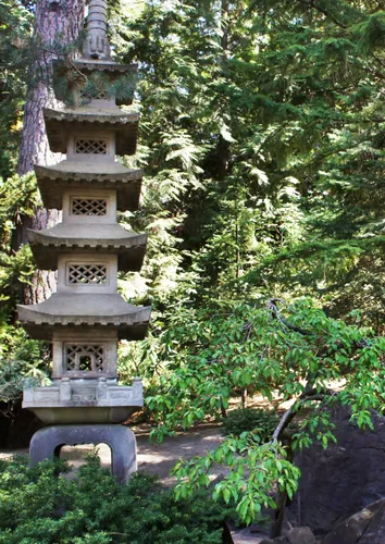 Traditional stone pagoda stands among foliage in Nishinomiya Tsutakawa Japanese Garden