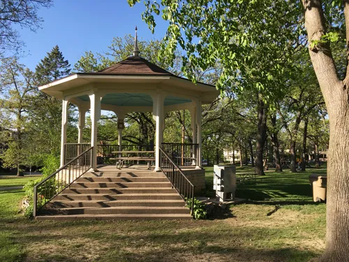 A gazebo with steps offers a charming focal point among the park's trees