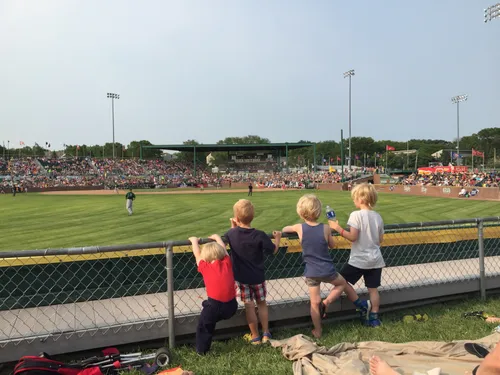 Kids watching a Madison Mallards baseball game from the outfield fence