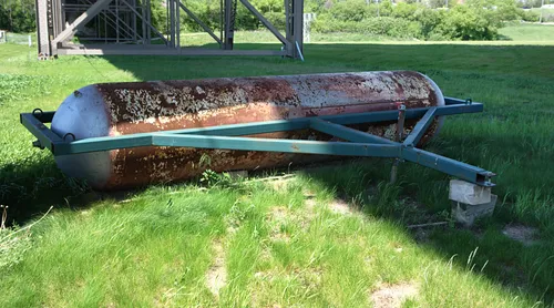 A roller rests in the grass below 35th Street Viaduct
